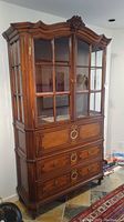 Full view of antique German hutch showing carved top, glass paneled doors, and lower drawers with brass ring handles.
