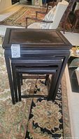 Three wooden nesting tables stacked together showing tops and frame.