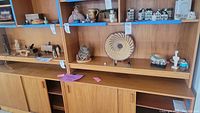 Wide view showing wooden shelves with various indigenous art pieces, basket, statues and tools.