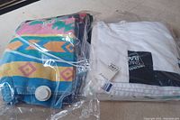 Colorful geometric patterned beach towel and white towel in vacuum space-saver bags