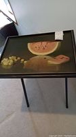 Single black folding TV tray with a picture of sliced watermelon and grapes on tray surface