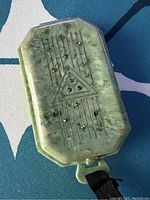 Top view of green marbled octagonal plastic compact with geometric art deco design and green rhinestones.