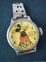 Front view of watch face showing painted yellow dial with Mickey Mouse and rotating arm hands