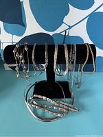 Sterling silver mixed necklaces and bracelets arranged on black display holder, various chain styles including beaded, twisted, flat, and snake chains visible.