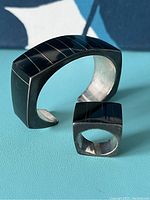 Ring and cuff side by side on turquoise surface showing gold ribbon inlay across black jade slabs