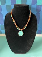 Full frontal photo of the necklace displayed on black velvet holder showing bead colors and pendant.