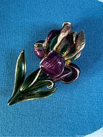 Front view of purple iris flower brooch pin with enamel detailing on petals and leaves.