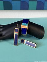 Cuff and two earrings arranged on black mannequin hand