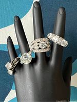Four sterling silver and rhinestone rings displayed on black hand mannequin to show detail and size variation.