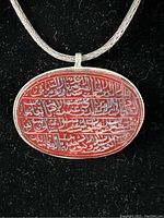 Close-up view of the oval carved agate pendant with Arabic calligraphy on sterling silver setting.