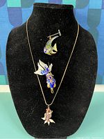 Front view showing all three cloisonné fish pendants and necklace displayed on black velvet stand.