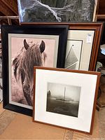 Three framed art prints displayed against a wall, showing a horse portrait, a geometric minimalist print, and a boat photograph.