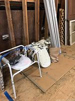 Three aluminum rail sections leaning against studs with portable commode chair and drive units at base