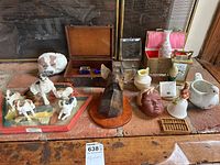 Full lot with assorted small boxes, dog figurines, carved wooden dog head on plaque, vases, brass clock, ceramic pieces, and cookie stamp.