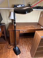 Full view of the BlueMax floor lamp, showing its black metal base, slender adjustable arm, and rectangular black lamp head with chrome trim.