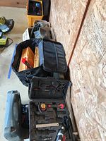 Overview of black soft-sided toolbox with tools inside, mini toolkit case, and cordless power tool charger