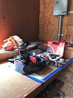 Photo showing Black & Decker circular saw, Skil cordless drill, soldering iron kit with solder wire and accessories on a wooden surface