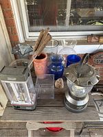 Photo showing seven vases, two lanterns, wine holder with wooden skewers, and marshmallow holders on a table outside porch area