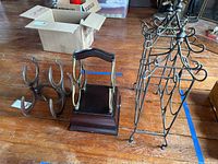 Photo showing the three wine racks: a horseshoe metal rack, a brass and wood rack with drawer in the center, and a decorative black metal rack with hooks.