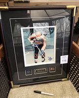 Framed autographed photo with plaque and pins shown on chair, showing overall lot.