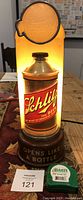 Photo showing full illuminated Schlitz Beer light-up sign with glass globe on top and 'Opens Like A Bottle' base.
