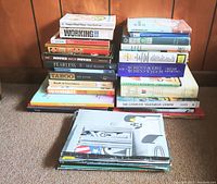 Three stacks of assorted books arranged on floor showing varied titles and subjects.