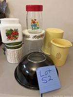 Overview of all items including the black Pyrex bowl, Tupperware canisters, various glass and ceramic canisters.