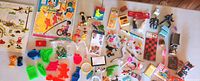 Wide angled photo showing various vintage charms, toys, plastic figurines, miniatures, and small board puzzles scattered on a white surface.