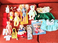 Wide shot of all dolls, clothes, plush toy, and accessories on red couch.