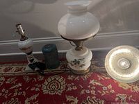 Side view of two glass lamps, blue oil diffuser, and silver hanging light on patterned carpet.