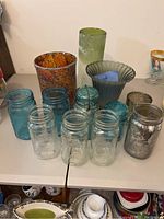 Overview of the Mason jars and decorative vases on a white surface showing brand markings and textures.