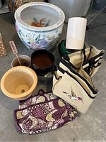 Large painted ceramic fishbowl pot next to several smaller planting pots and garden bags, showing overall lot contents