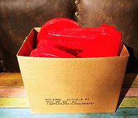 Box filled with multiple large, glossy red plastic sign letters, some stacked showing thick 3D plastic shapes.