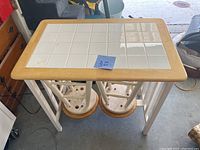 Top view of a rectangular breakfast table with white tiled top and wooden trim.
