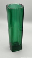 Tall emerald green vase with vertical ridged inner texture and smooth outer surface, standing upright.