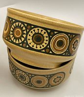Close-up of two stacked stoneware bowls showing Bacchus pattern in mustard yellow and brown with circular geometric design
