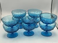 Set of 10 blue glass footed dessert dishes grouped together, showing shape and vibrant color