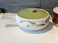 Photo of the covered casserole dish showing green lid and botanical Spring pattern on cream base with handle.