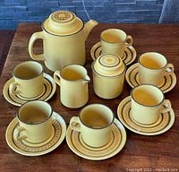 Complete set arranged on wood surface including cups and saucers, creamer, sugar bowl, and teapot.