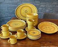 Full set arranged on table showing all six each of dinner plates, cereal bowls, side plates, cups, saucers and two platters
