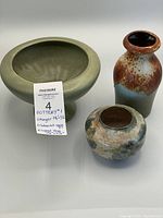 Three pottery pieces: Haeger footed planter, Scheurich vase and studio pottery vase grouped together on white surface