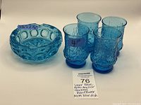 Four laser blue Anchor Hocking Rainflower glasses and one aqua blue glass ashtray displayed together on white background, showing size and color contrast.
