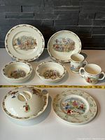 Photo of all 9 pieces arranged on tabletop showing full set including large plates, bowls, mugs, and covered bowl