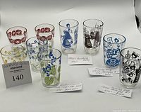 Photo shows 9 Swanky Swigs glasses with colorful mid-century decorations standing on white backdrop with visible labels describing glass names and sizes.