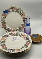 Photo showing 8 stacked floral plates, purple art glass vase, and Wade decorative plate with visible size labels
