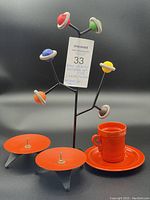 Full lot photo showing the metal tree with colourful wooden balls, two orange metal candle holders, and orange cup with saucer