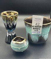 Set of three West German pottery items: two vases and one planter showing drip glaze colors and gold trim.