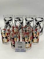 Full set of 10 glasses, 4 Libbey tumblers in back row with black pattern, 6 Sasaki glasses in front row with red, gold, and black geometric designs and labels on 5