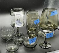 Photo showing 10 pieces of green smoky vintage smoked glassware including various sizes and shapes with height labels on some pieces from 3 to 7 inches.