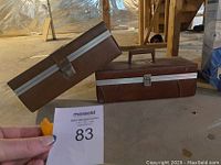 Two closed brown vintage 8-track cases placed on floor showing the exterior design and metal trims